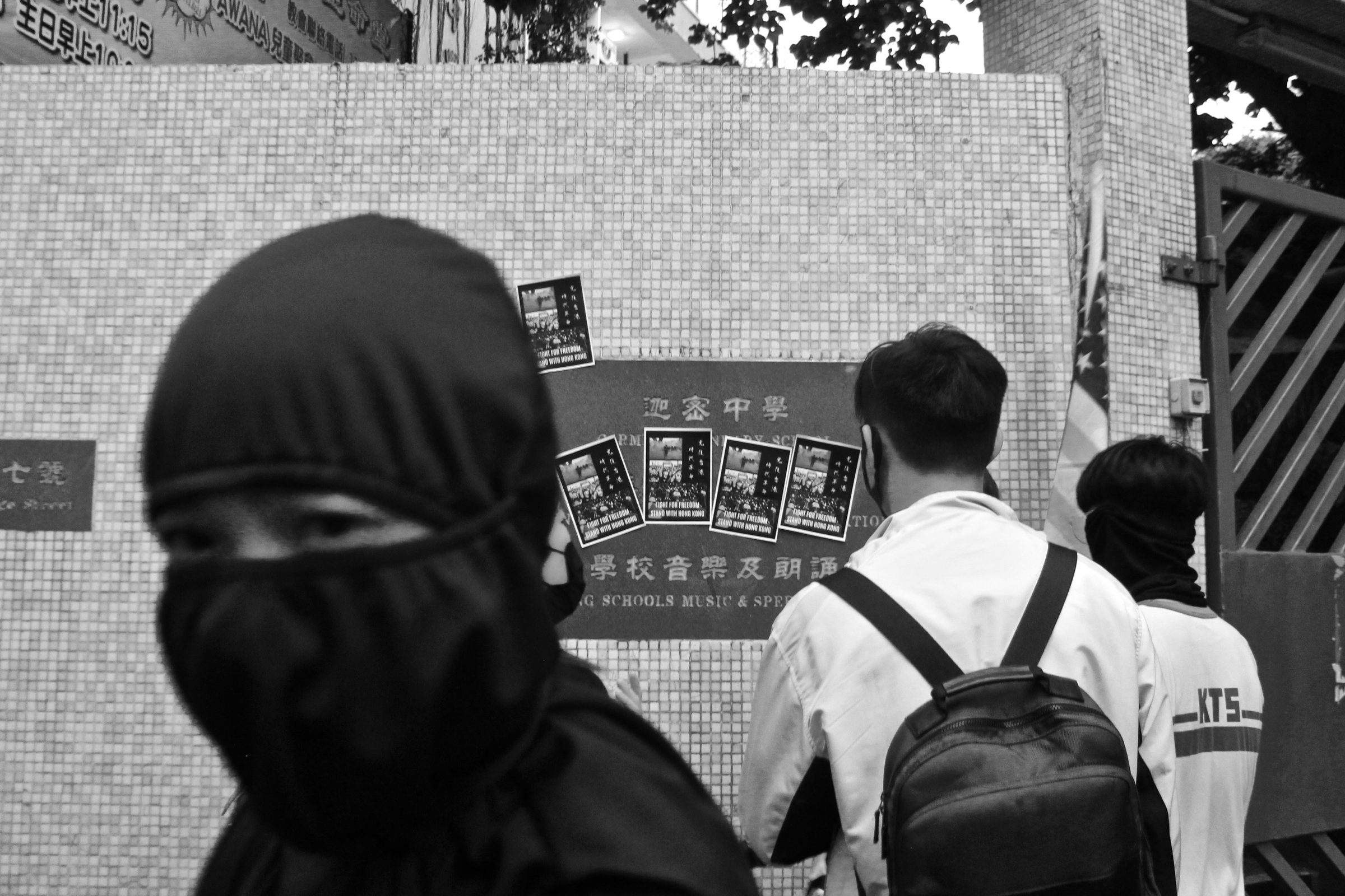 Masked figures beside protest posters, Hong Kong