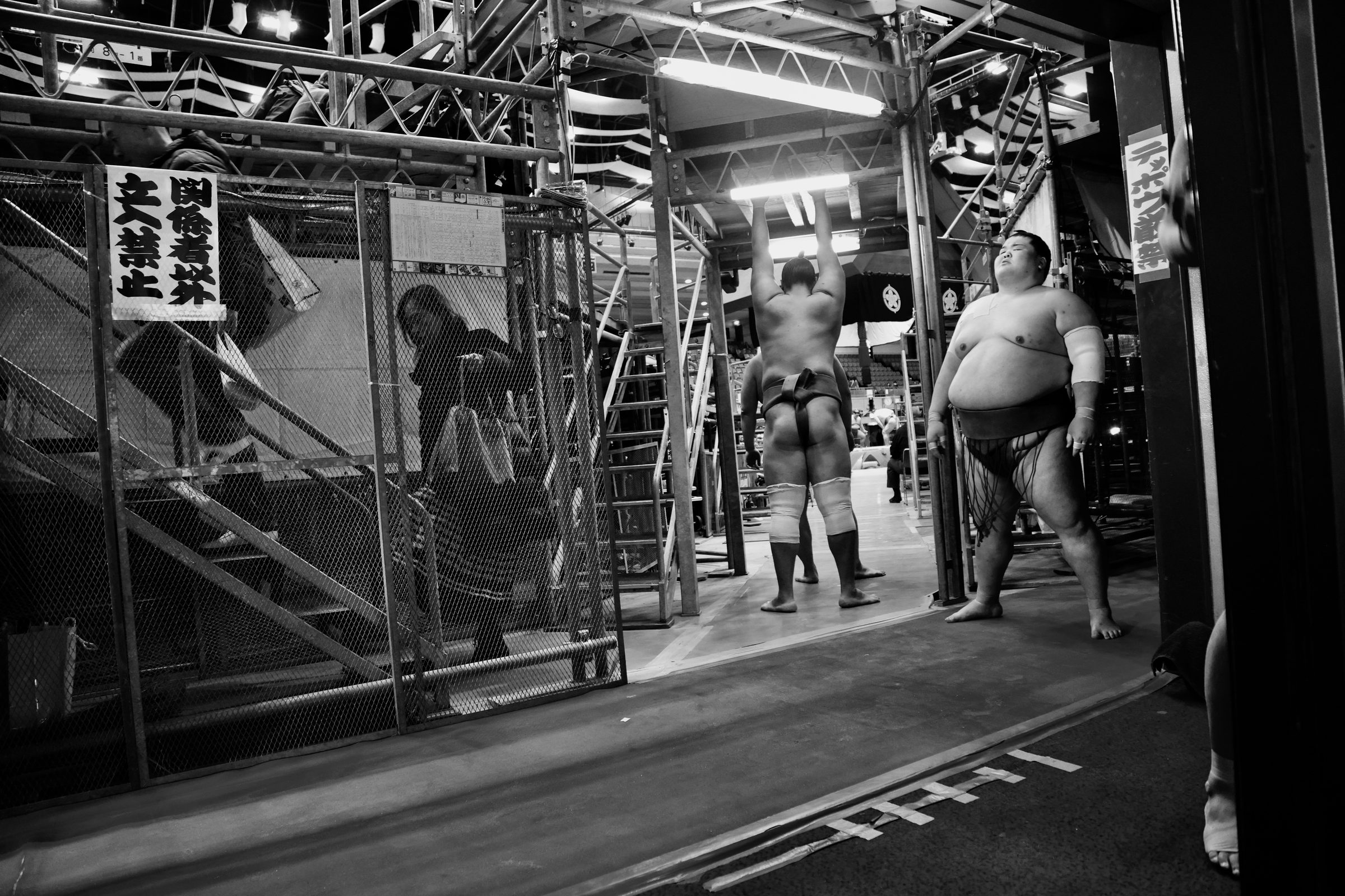 Sumo wrestlers stretching backstage